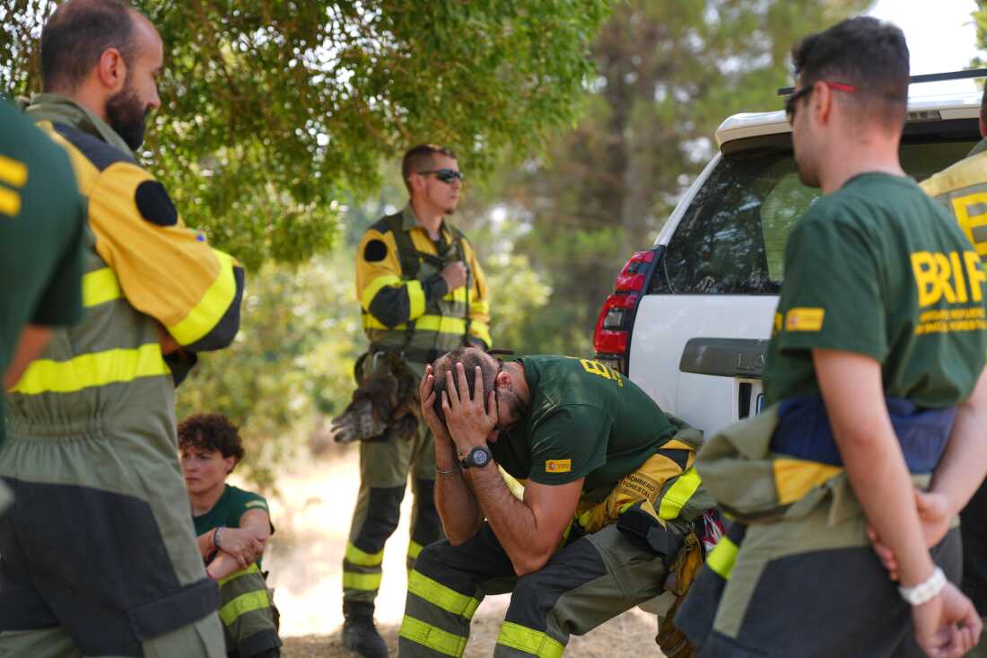 Aesir Díaz, de 31 años, técnico de las Brigadas de Refuerzo contra Incendios Forestales de España (BRIF), en el centro, se sienta junto a sus compañeros de equipo durante un descanso en la lucha contra un incendio forestal en Sotillo de Adrada, provincia de Ávila, España, mientras el fuego continúa propagándose, el martes 28 de julio de 2026.
